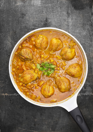 chicken leg with chickpeas and curry sauce in white pan on old gray wooden table, Indian cuisineの写真素材