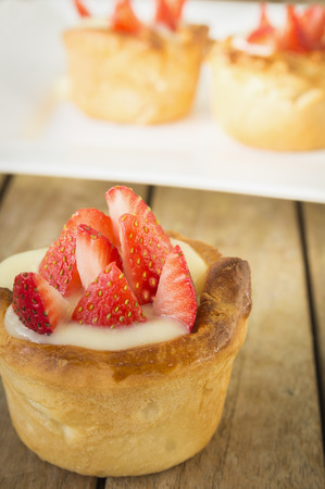 Mini tart with custard and strawberries on rustic tableの写真素材