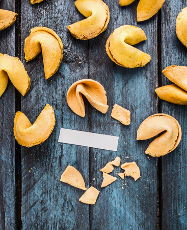 break fortune cookie with blank paper tag on blue wooden background, top view, coipy spaceの写真素材