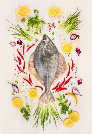 Raw flounder fish with fresh seasoning, lemon and spices on rustic wooden background withe, top viewの写真素材