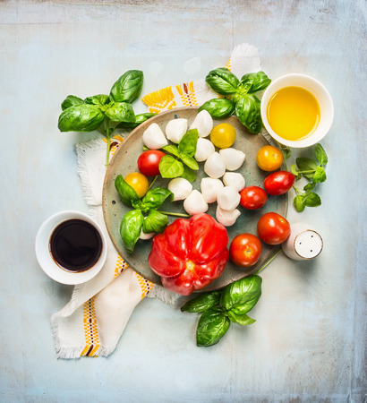 Italian mozarella salad tomatoes, balsamic vinegar and ingrediets with oil on rustic wooden background, top viewの写真素材