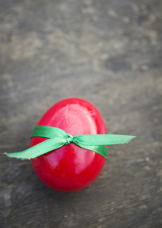 Red easter egg with green ribbon on old wooden background Top Viewの写真素材