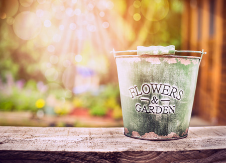 Empty bucket on old wooden table over summer or autumn garden background horizontalの写真素材