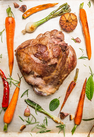 Roast leg of lamb with herbs and baked vegetables on old metal background, top viewの写真素材