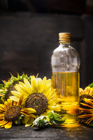 bottle of Sunflower oil with fresh blooming on dark wooden backgroundの写真素材