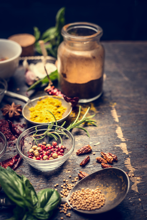 Assorted ground spices in bowls, spoon and  bottles over dark wooden backgroundの写真素材