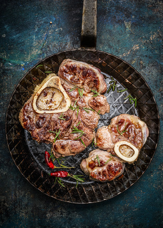 Roasted veal shank slices in frying pan on rustic background, top view, close upの写真素材
