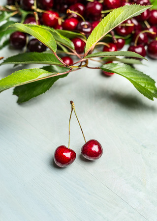 Ripe cherries with branches and leaves on rustic wooden backgroundの写真素材