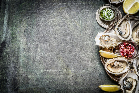 Appetizer Oysters plate with lemon and sauces on rustic background, place for text