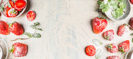 Sweet strawberries  with  powdered sugar  and mint leaves  on white shabby chic wooden background, top view, bannerの写真素材