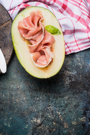 Half of melon and Prosciutto ham on rustic background, top view, place for text.  Italian food conceptの写真素材