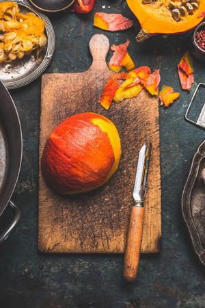 Pumpkin peeling on rustic cutting board with vegetables peeler , dark wooden background, top viewの写真素材