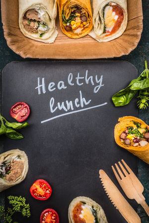 Healthy lunch Lettering  with vegetarian wraps and wooden cutlery on dark chalkboard, top view, frameの写真素材