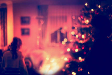 Blurred home Christmas scene with Christmas  tree, gifts , festive bokeh lighting and silhouette of girlの写真素材