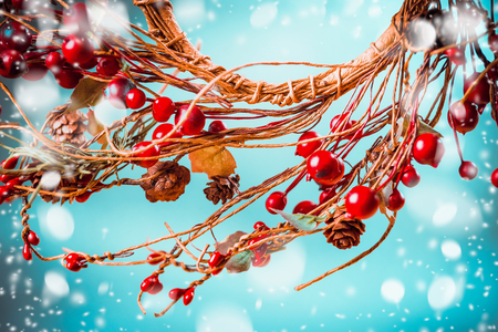 Christmas red berries wreath on blue background with snow, festive greeting cardの写真素材