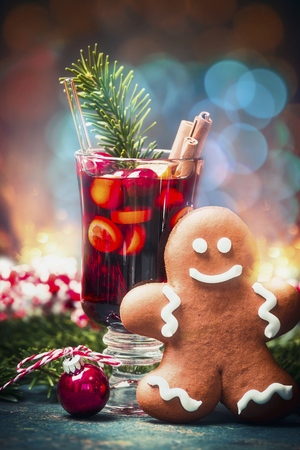Mug of Mulled wine and gingerbread man with Christmas decoration at festive bokeh background,  front viewの写真素材