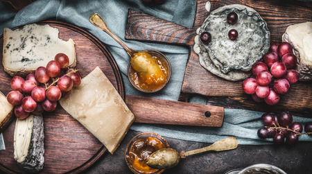 Assorted cheeses on rustic cutting boards with grape and honey mustard sauces, top viewの写真素材