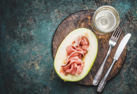 Italian antipasti with ham , melon and wine served with cutlery  on rustic background, top viewの写真素材
