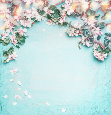 Beautiful spring nature background with lovely blossom, petal and bokeh on turquoise blue background , top view, frame. Springtime concept