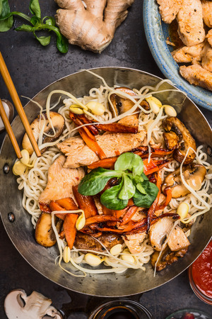 Wok with noodles chicken stir fry and chopsticks, top view, close up. Asian cuisine conceptの写真素材