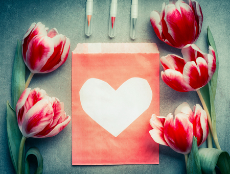 Paper envelope with heart , fresh lovely tulips flowers and brush markers, top view, copy space. Abstract love and greeting conceptの写真素材
