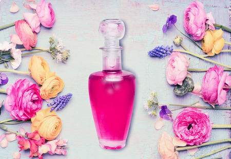 Bottle of perfume and flowers at shabby chic background, top view. Floral cosmetic and beauty...
