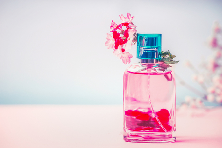 Pink Bottle of perfume with flowers, natural cosmetic product or beauty concept on pastel blue background, front viewの写真素材