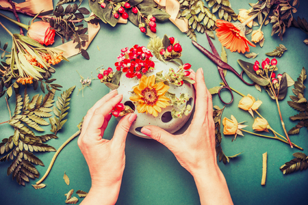 Female hands making autumn flowers arrangements in vase, top viewの写真素材
