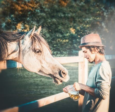Young guy with horse holds a beer mug in his handの写真素材