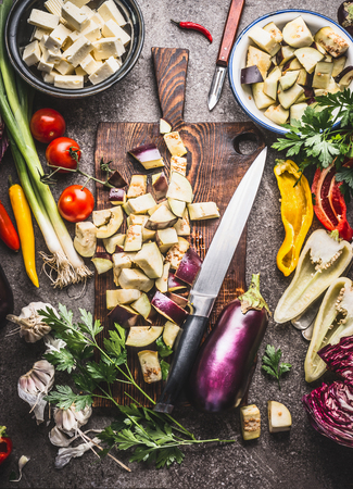 Chopped eggplant on wooden cutting board with knife and various vegetarian cooking ingredients for healthy eating , top view. Balkan cuisine conceptの写真素材