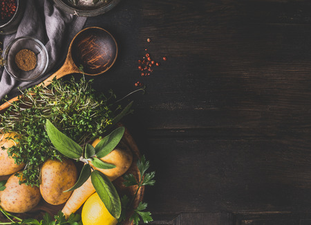 Food and cooking background with vegetables , flavor herbs and cooking spoon on dark rustic background, top view, place for textの写真素材