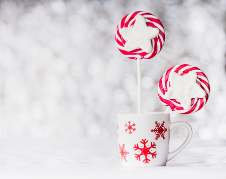 Mug with snowflakes and  Christmas candies on bokeh background, front viewの写真素材