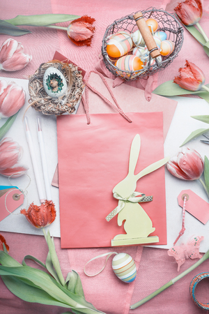 Easter greeting layout with tulips,eggs, and decor bunny on shopping bag on pastel color backgroundの写真素材