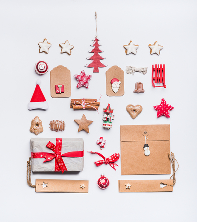 Christmas layout with craft paper wrapping gift boxes, tags, cookies, red holiday decoration, present, spices, Santa hat and red Christmas tree on white desk background, top view, flat lay.の写真素材