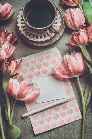 Fresh pink pale tulips with heart , blank paper , marker and cup of coffee , top view. Nostalgic Mother day greeting card or spring holidays mock upの写真素材