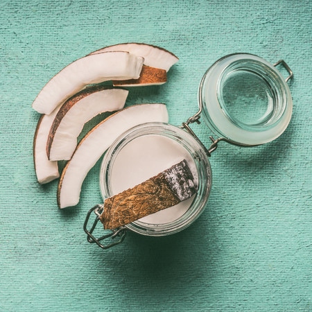 Coconut milk in glass jar with coconut slices on turquoise background, top view . Detox, dieting, clean eating, vegetarian, vegan, fitness or healthy lifestyle conceptの写真素材