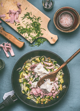 Tasty zucchini ham fresh cheese filling or sauce in cooking pan on kitchen table with ingredients, top viewの写真素材