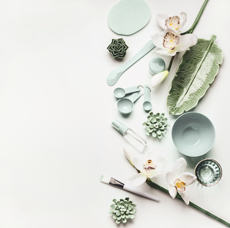 Modern cosmetic skin care flat lay setting with tools and accessories for  facial mask making: Mask Brush, bowl, spatula, measuring spoons and flowers on white desktop background, top viewの写真素材