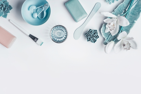 Blue Cosmetic setting for facial skin care with white orchid flowers, homemade mask tools and accessories on white background, top view, place for text. Beauty and nature herbal cosmetic conceptの写真素材