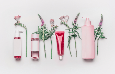 Pink herbal natural facial cosmetic products set with herbs and flowers on white background, top view. Branding mock upの写真素材
