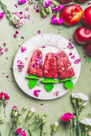 Homemade fruits and berries ice cream   on plate , decorated with garden flowers on teal rustic green table background, top view. Vintage style. Country style summer foodの写真素材