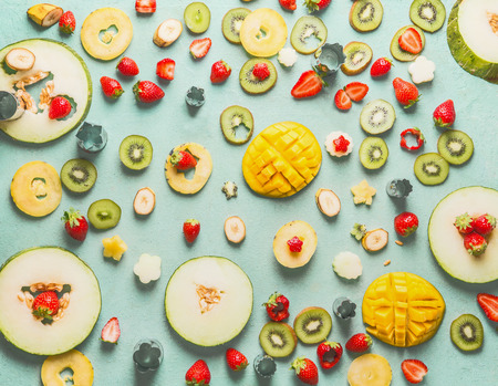 Various sliced fruits and berries on light blue background, top view, flat lay. Summer healthy food concept. Fruits salad ingredients selectionの写真素材