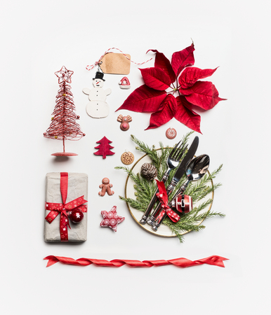 Christmas concept. Various holiday objects: gift, Christmas tree, table place setting with cutlery and decorations, fir  branches, pine cones and poinsettia on white background. Flat lay, top viewの写真素材