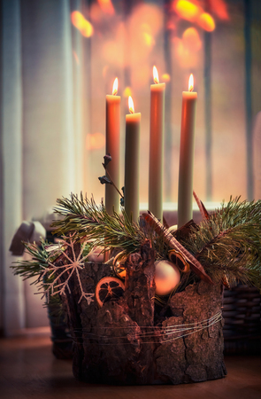 Cozy Christmas time at home.  Advent wreath with four burning candles. Winter decor interior with warm bokeh lighting. Christmas eveの写真素材