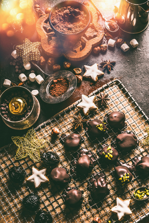 Homemade chocolate praline on dark rustic table with cacao powder , nuts, marshmallows and cinnamon star Christmas cookies. Home holidays cuisine and sweet gifts making. Christmas foodの写真素材