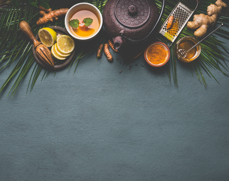 Healthy turmeric spice tea with lemon,  ginger and honey on dark background with copy space for your design, top view, border. Immune boosting remedy , detox and dieting conceptの写真素材