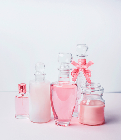 Variety of pink cosmetic product bottles and  flowers standing on white pinkの写真素材