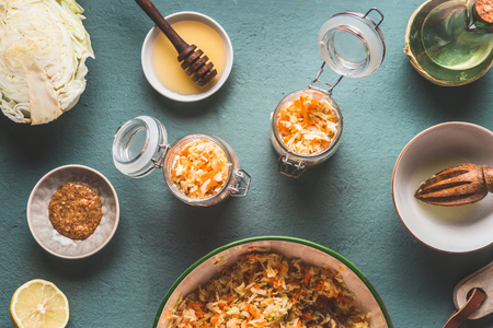 Preparation of carrot cabbage salad in jars for healthy lunch is on kitchen table background, top view, with copy space. Vegetarian food, low-calorie vegetable eating and weight loss dieting conceptの写真素材