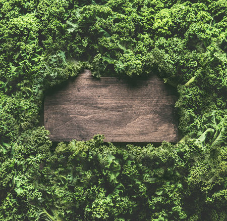 Kale leaves background frame with wooden sign. Healthy detox vegetables . Clean eating and dieting concept. Top view with copy space. Kale recipes and  benefitsの写真素材