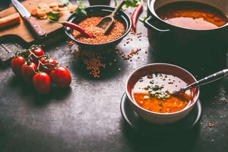 Healthy vegan lentil soup in bowl with spoon on dark kitchen table background with ingredients. Vegetarian food. Clean diet eating. Source of plant based proteinの写真素材